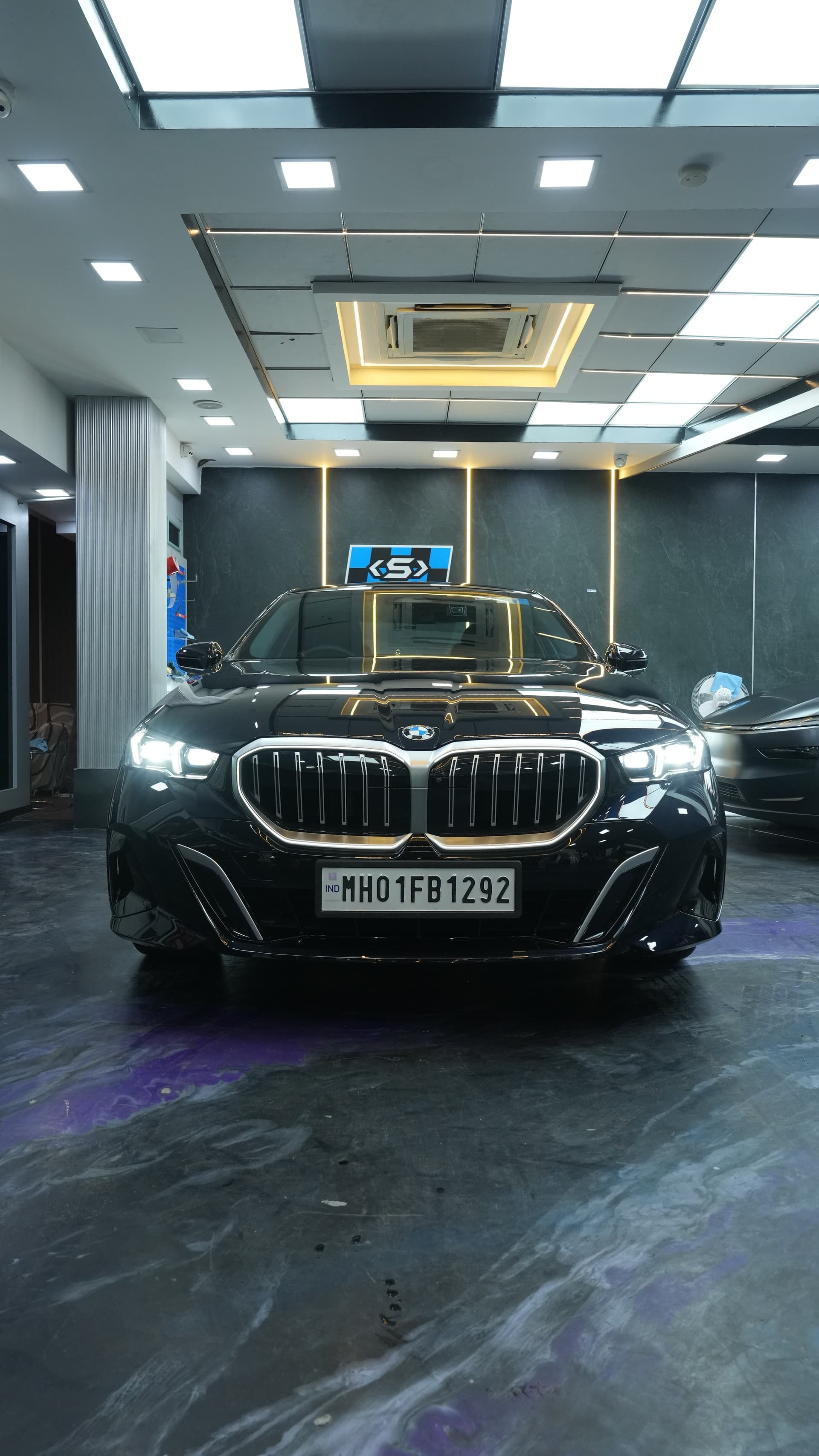 Black BMW 5 Series under studio lights after full-body paint protection film at Carsuit Worli