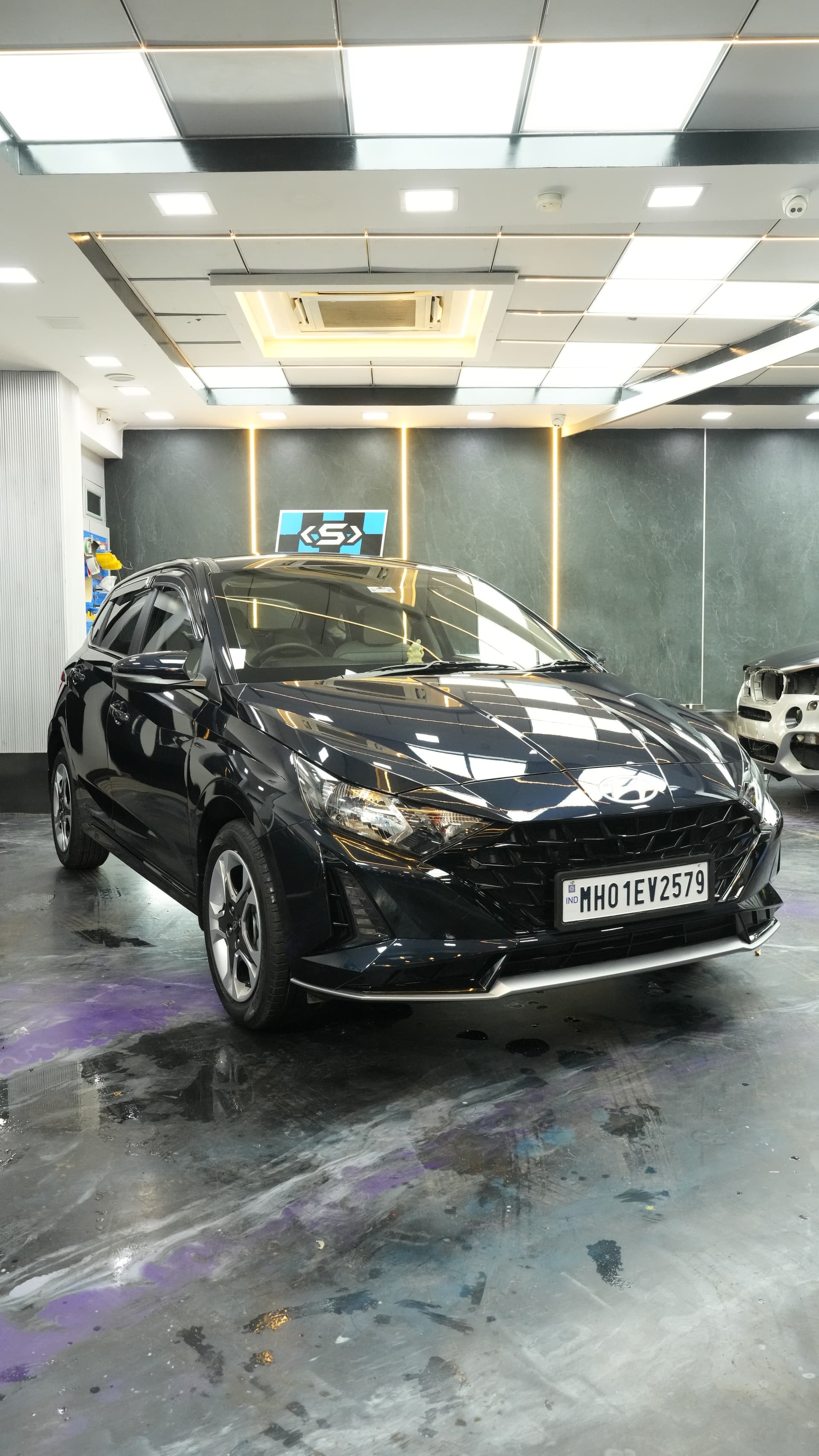 Freshly painted black hatchback curing under studio lights at Carsuit Mumbai